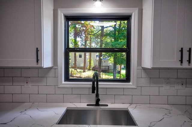 kitchen featuring light stone counters, tasteful backsplash, and sink