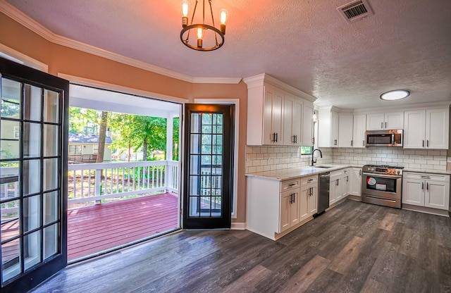 kitchen with pendant lighting, dark hardwood / wood-style floors, white cabinets, an inviting chandelier, and stainless steel appliances