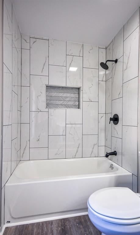 bathroom with tiled shower / bath, toilet, and hardwood / wood-style flooring