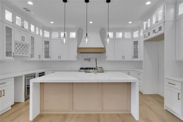 3893 Indian Shoals Rd, Dacula, GA 30019 - kitchen with custom exhaust hood, light wood finished floors, white cabinets, a kitchen island, and recessed lighting