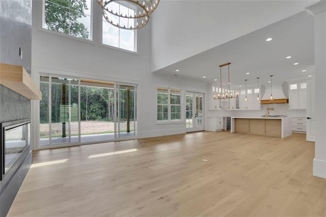 3893 Indian Shoals Rd, Dacula, GA 30019 - unfurnished living room featuring a chandelier, a high ceiling, light wood finished floors, a glass covered fireplace, and recessed lighting