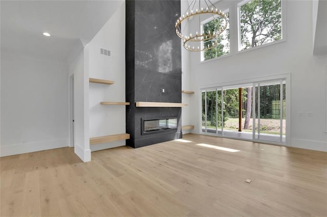 3893 Indian Shoals Rd, Dacula, GA 30019 - unfurnished living room with a high ceiling, a chandelier, a fireplace, wood finished floors, and recessed lighting