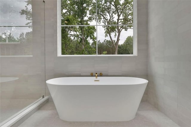 3893 Indian Shoals Rd, Dacula, GA 30019 - bathroom with a soaking tub, tile walls, tile patterned flooring, and plenty of natural light