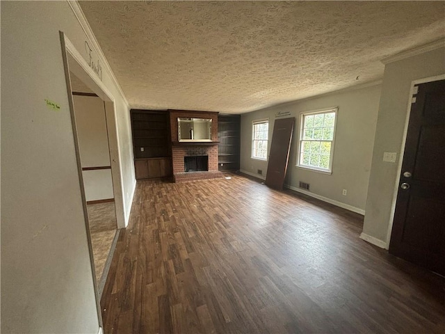 unfurnished living room featuring baseboards, dark wood finished floors, ornamental molding, a textured ceiling, and a brick fireplace