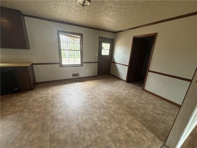 interior space with a textured ceiling, visible vents, baseboards, tile patterned floors, and crown molding