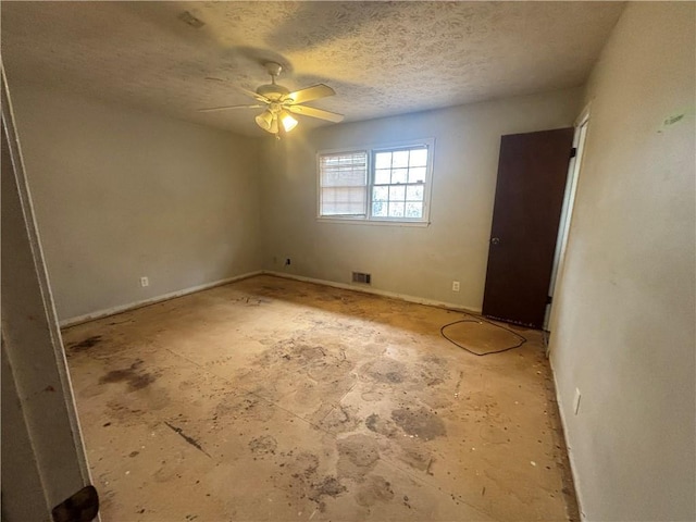 empty room featuring ceiling fan, visible vents, and a textured ceiling