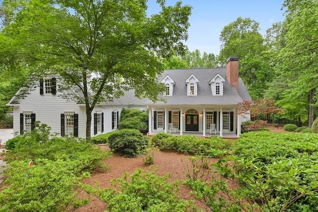 cape cod house featuring a porch and a chimney