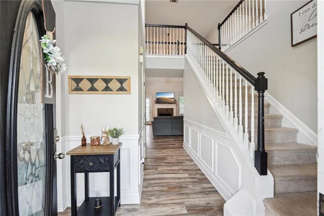 45 Peregrine Ln S, Dawsonville, GA 30534 - stairs featuring a wainscoted wall, a towering ceiling, wood finished floors, a decorative wall, and a fireplace