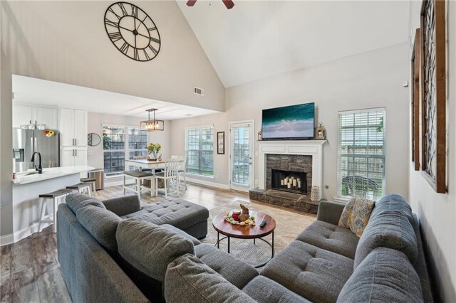 45 Peregrine Ln S, Dawsonville, GA 30534 - living room featuring high vaulted ceiling, a stone fireplace, wood finished floors, ceiling fan with notable chandelier, and visible vents