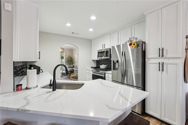 45 Peregrine Ln S, Dawsonville, GA 30534 - kitchen featuring a sink, arched walkways, a peninsula, appliances with stainless steel finishes, and white cabinetry