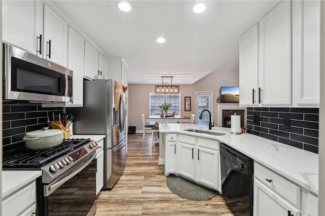 45 Peregrine Ln S, Dawsonville, GA 30534 - kitchen featuring a peninsula, light wood-style flooring, a sink, white cabinetry, and appliances with stainless steel finishes