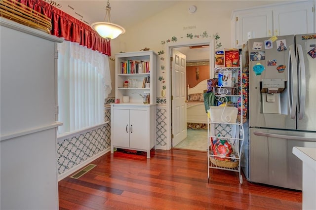 kitchen with stainless steel refrigerator with ice dispenser, wood finished floors, healthy amount of natural light, white cabinets, and wallpapered walls