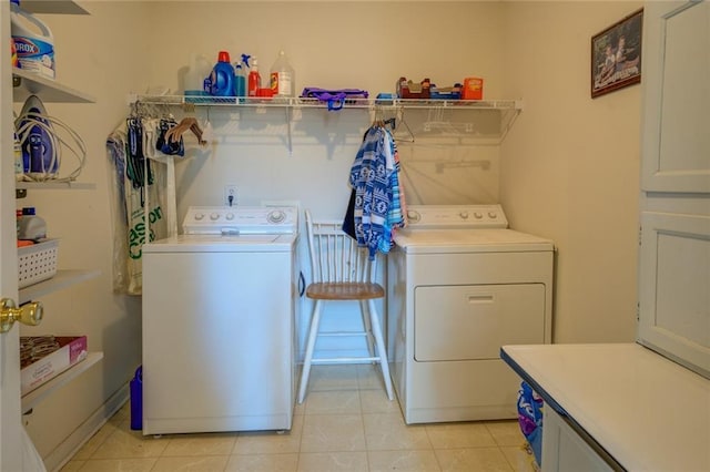 washroom featuring washing machine and clothes dryer, light tile patterned flooring, and cabinet space