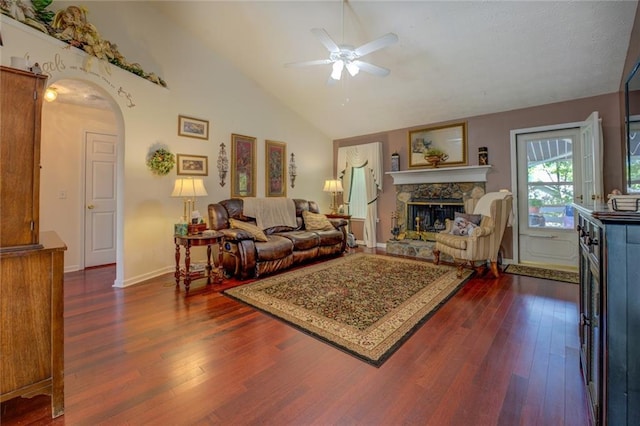 living area with ceiling fan, dark wood-style flooring, arched walkways, a fireplace, and baseboards