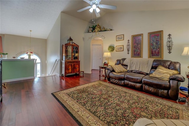 living area with high vaulted ceiling, a ceiling fan, hardwood / wood-style flooring, and arched walkways