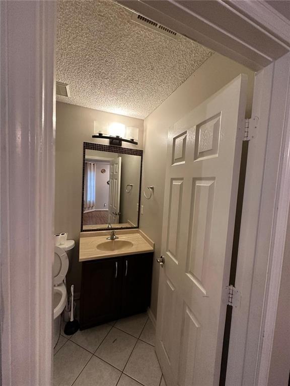 bathroom featuring toilet, tile patterned flooring, and vanity