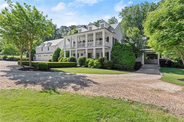 view of front of home with gravel driveway, a front lawn, a balcony, and metal roof