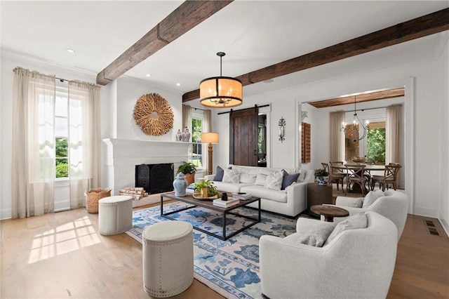 living room featuring a barn door, a chandelier, wood finished floors, beam ceiling, and baseboards