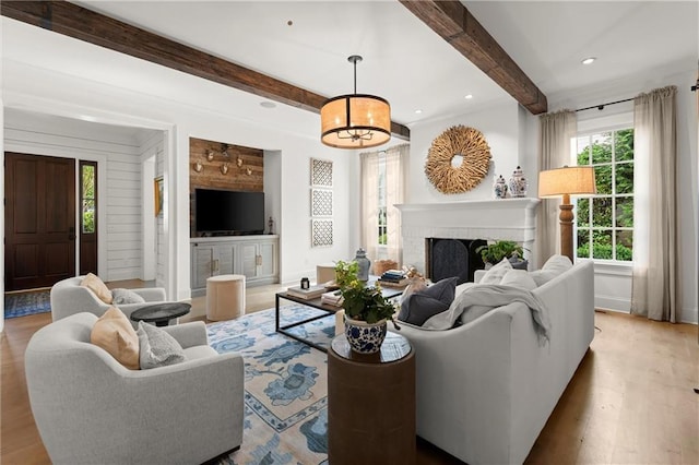 living area with wood finished floors, beamed ceiling, a fireplace, recessed lighting, and a chandelier