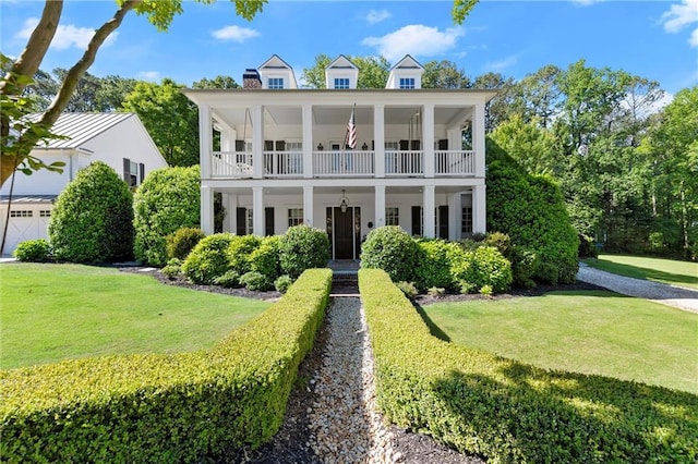 greek revival house featuring a front lawn, a balcony, and a chimney