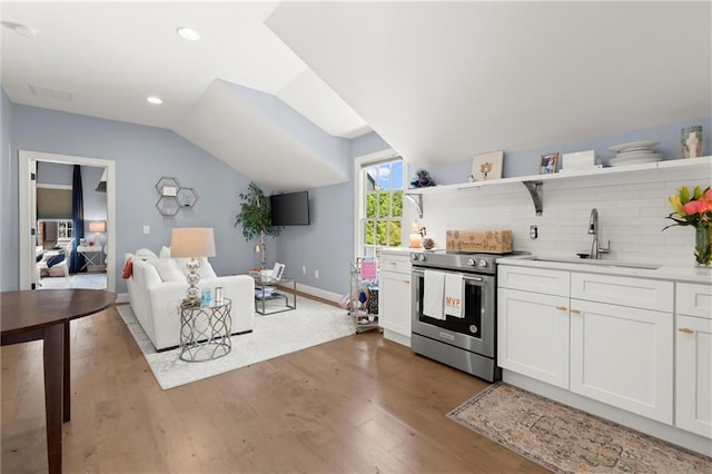 kitchen with electric stove, a sink, open shelves, wood finished floors, and vaulted ceiling