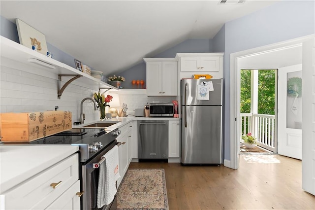 kitchen featuring appliances with stainless steel finishes, open shelves, a sink, decorative backsplash, and white cabinetry