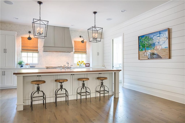 kitchen featuring a chandelier, healthy amount of natural light, custom range hood, and wood finished floors