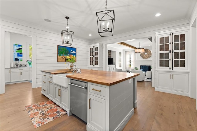 kitchen with butcher block countertops, dishwasher, white cabinets, light wood finished floors, and hanging light fixtures