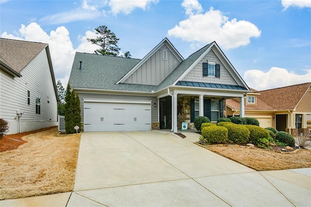 craftsman-style home featuring driveway, a garage, stone siding, covered porch, and board and batten siding