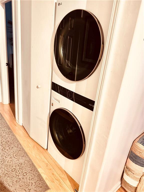 washroom featuring stacked washer and clothes dryer and light wood-type flooring