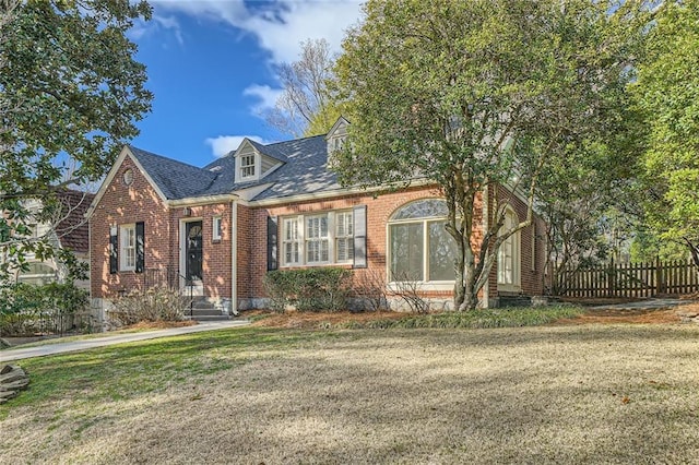 view of front of house featuring brick siding, a front yard, and fence