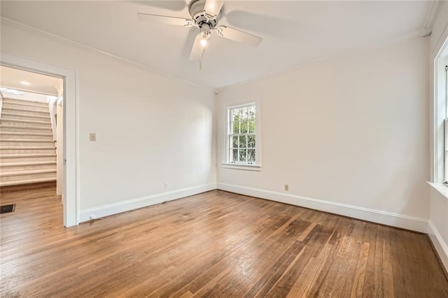 unfurnished room with visible vents, ornamental molding, a ceiling fan, hardwood / wood-style floors, and baseboards