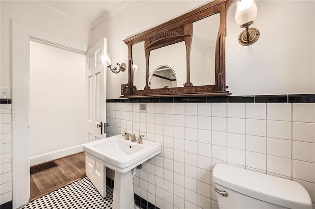 bathroom featuring visible vents, toilet, wood finished floors, tile walls, and crown molding