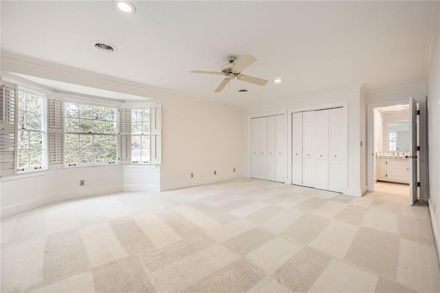 unfurnished bedroom featuring recessed lighting, baseboards, multiple closets, and crown molding