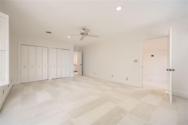 unfurnished bedroom featuring baseboards, crown molding, and multiple closets