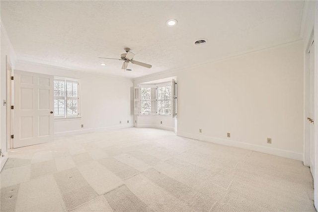 spare room featuring baseboards, plenty of natural light, visible vents, and crown molding