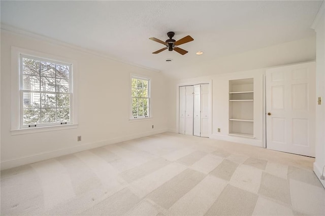 unfurnished bedroom with light carpet, a ceiling fan, crown molding, and baseboards