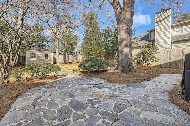 view of patio featuring an outdoor structure and a fenced backyard