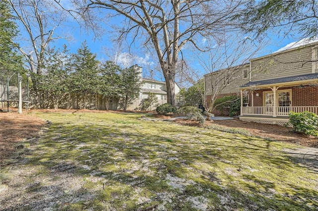 view of yard featuring covered porch and fence