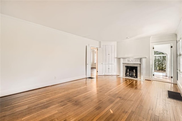 unfurnished living room featuring hardwood / wood-style floors, crown molding, baseboards, and a high end fireplace