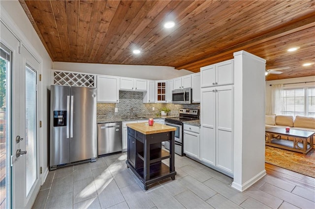 kitchen with stainless steel appliances, butcher block countertops, a sink, white cabinetry, and tasteful backsplash