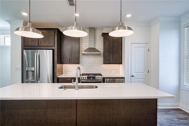 kitchen featuring pendant lighting, sink, dark brown cabinetry, stainless steel appliances, and wall chimney range hood