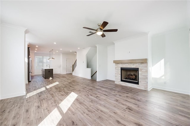 unfurnished living room with ceiling fan, ornamental molding, sink, and light hardwood / wood-style flooring