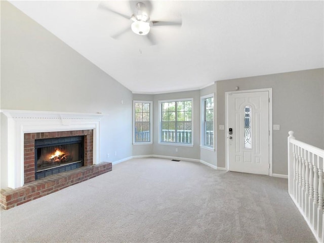 unfurnished living room featuring ceiling fan, light colored carpet, a fireplace, and vaulted ceiling