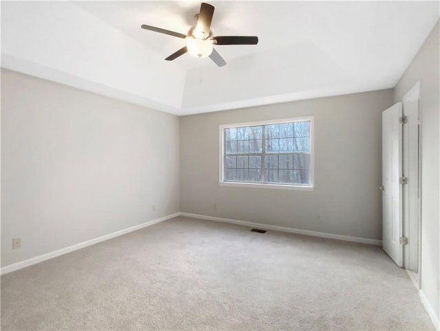 empty room featuring light carpet, a tray ceiling, and ceiling fan