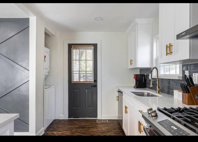 205 Maple St, Atlanta, GA 30354 - kitchen with decorative backsplash, white cabinets, stacked washing machine and dryer, wall chimney exhaust hood, and light countertops