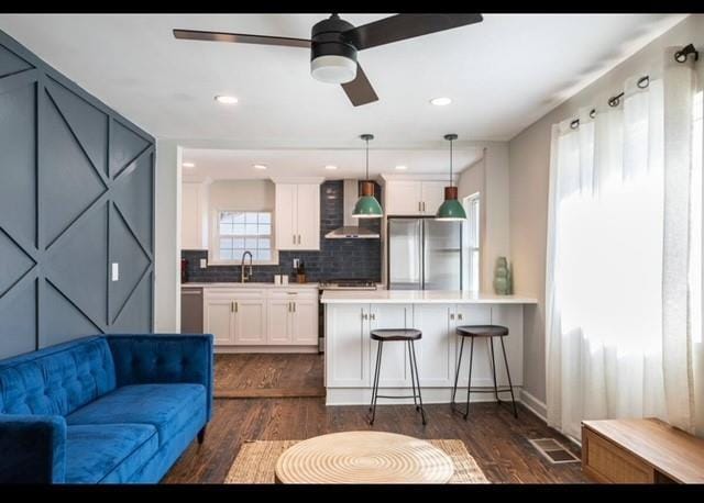 205 Maple St, Atlanta, GA 30354 - kitchen featuring freestanding refrigerator, wall chimney exhaust hood, white cabinetry, a kitchen breakfast bar, and dark wood-style flooring