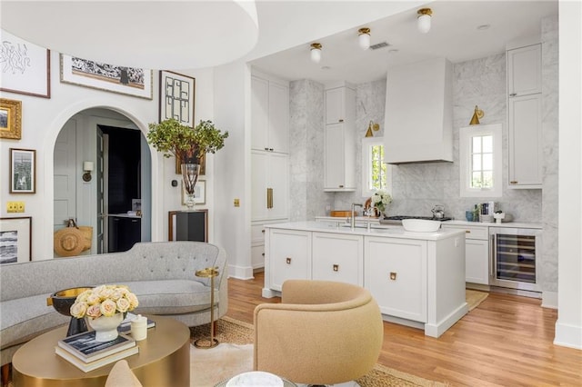 kitchen with light wood-type flooring, white cabinetry, and wine cooler