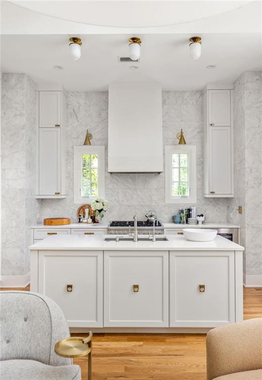 kitchen featuring premium range hood, white cabinetry, a healthy amount of sunlight, and light hardwood / wood-style floors