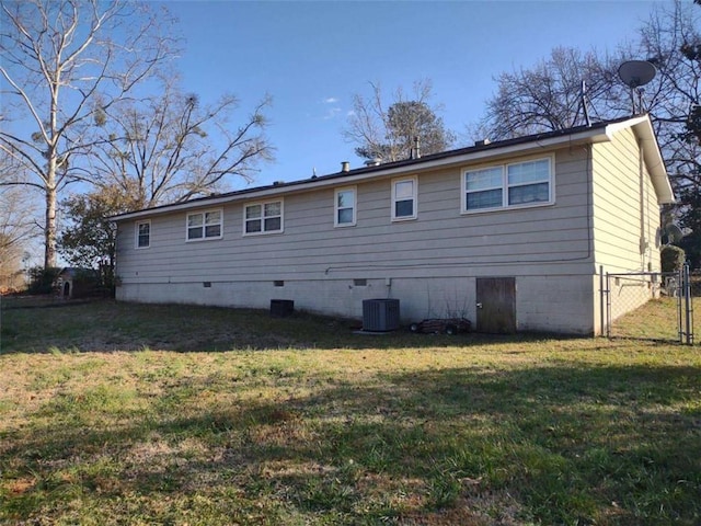 rear view of house featuring central AC and a lawn